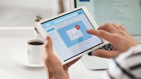 Hände halten ein Tablet welches Informationen anzeigt